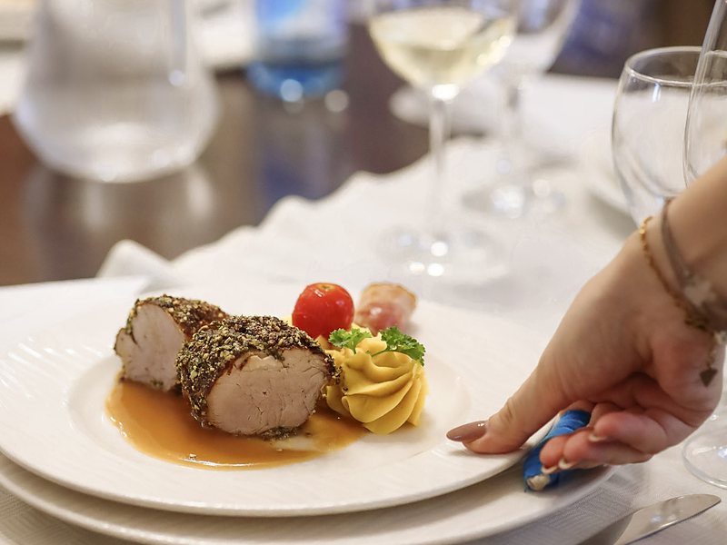 Glavno jelo na tanjuru uz čašu bijelog vina na gastro postaji Cipelcuga