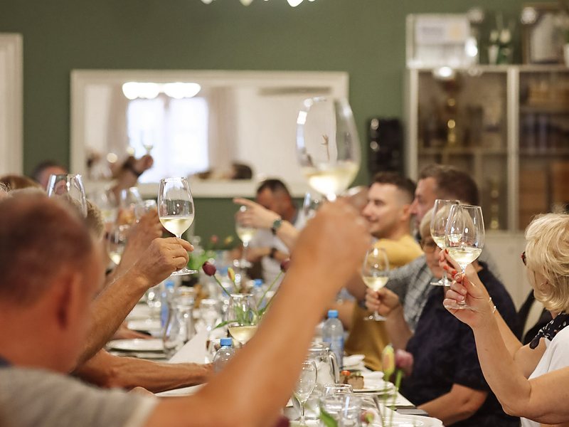 Sudionici nazdravljaju čašama vina za dugim stolom u restoranu